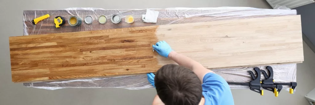 A young boy applying finishing agents on wood with proper safety precautions